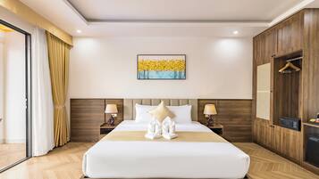 A hotel room with a large bed, wooden headboard, two bedside tables with lamps, a wall-mounted artwork, and a wardrobe with a hanging rack.
