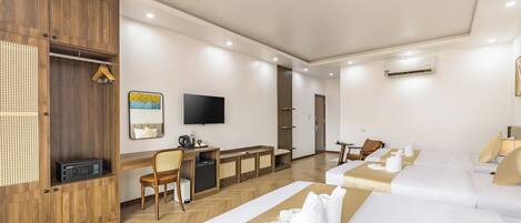 Quarto de hotel moderno com guarda-roupa de madeira, uma escrivaninha com cadeira, televisão de tela plana, sofá e uma cama.