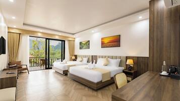 A hotel room with two beds, a desk, a chair, a TV, and a balcony with a view of mountains.