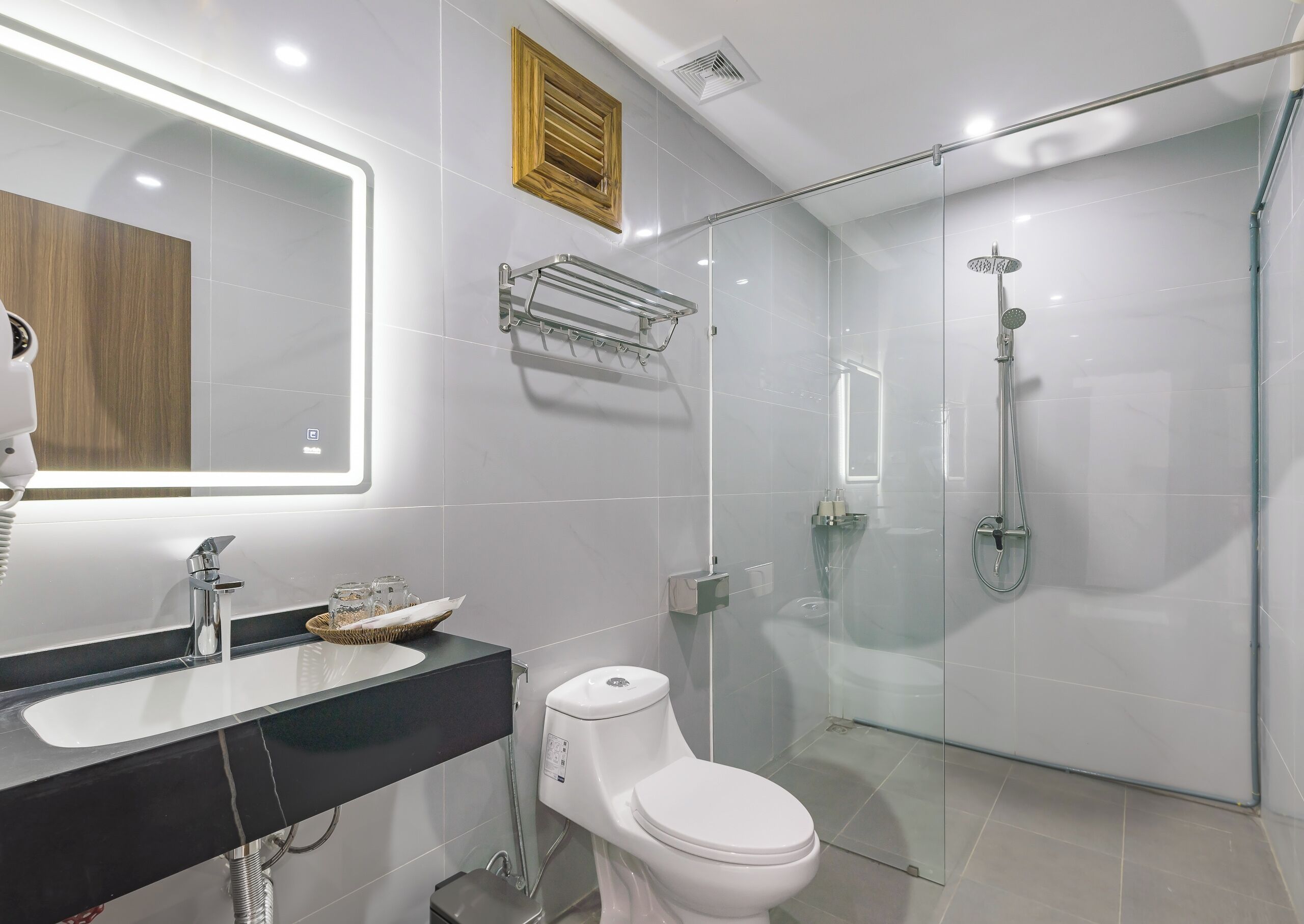A modern bathroom with a glass-enclosed shower, a vanity with a mirror, and a toilet.
