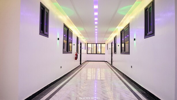 A hotel hallway with a fire extinguisher, a fire alarm, and a ceiling with LED lighting. - Skycity Hotel Gh (Amrahia)