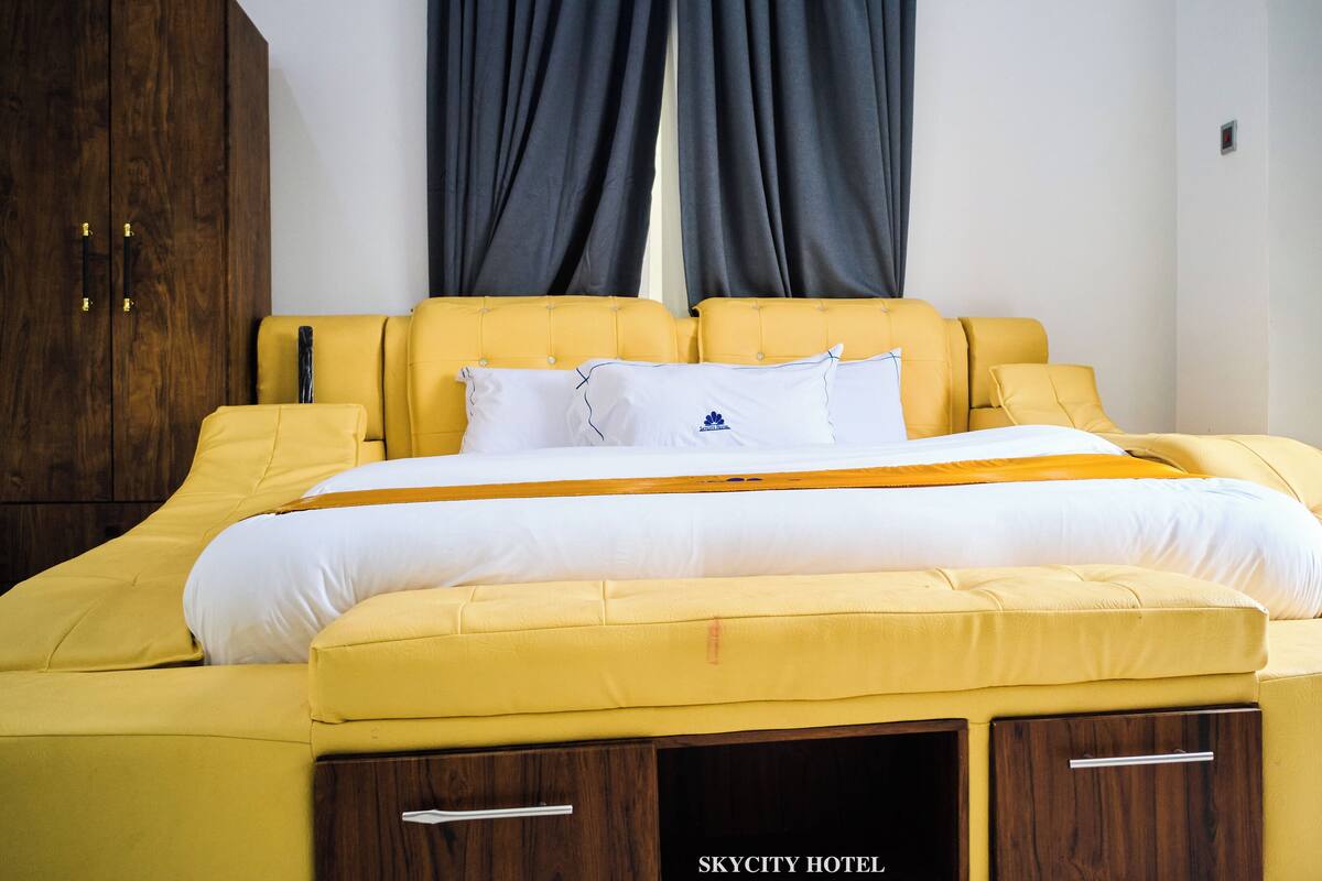 Habitación de hotel con una cama grande, un armario de madera y vistas a la ciudad.