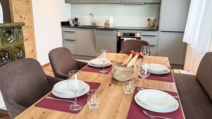 Ein Essbereich mit einem Holztisch, gedeckt für vier Personen, inklusive Tellern, Gläsern und einem Brotkorb.