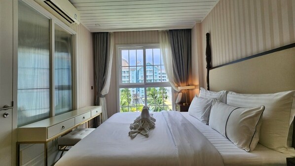 A hotel room with a large bed, a bedside table, a mirror, and a window with curtains.
