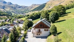 A rural village with traditional houses, a paved road, and a mountainous backdrop.