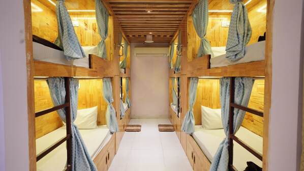A corridor with bunk beds, wooden walls, and curtains. - Deccan Dormitory (Hyderabad)