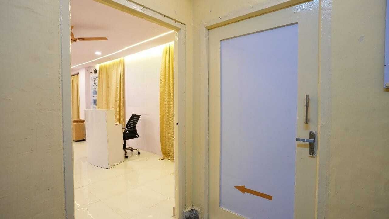 Un pasillo con una puerta cerrada a la derecha y un escritorio con una silla al fondo.