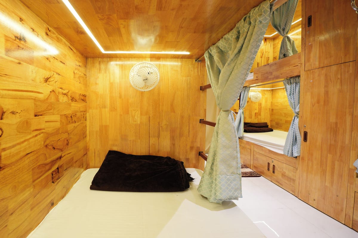 Une chambre dans un chalet en bois, équipée d’un lit, d’un ventilateur et d’un miroir.