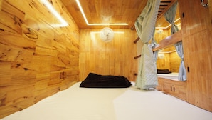 Ein Zimmer in einer Holzhütte mit einem Bett, einem Deckenventilator und einem Spiegel.