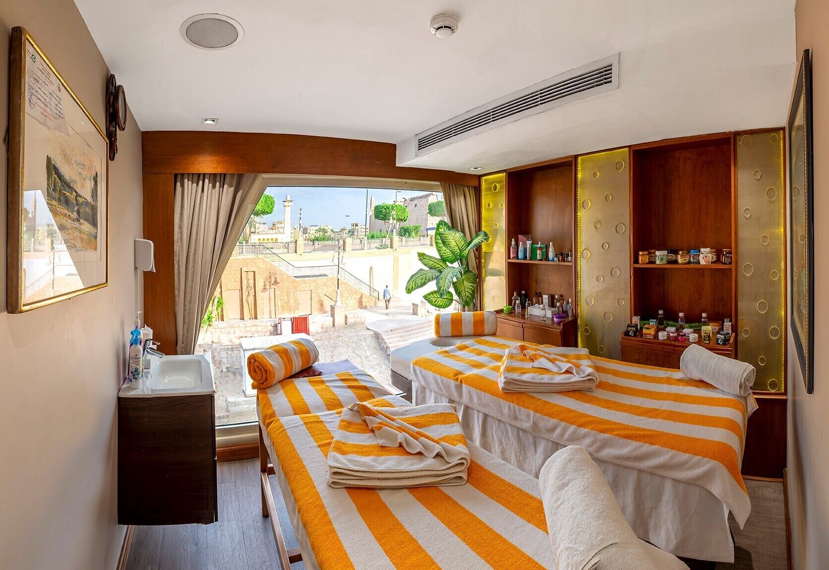 A hotel room with two beds, a small bathroom, a minibar, and a view of the city.
