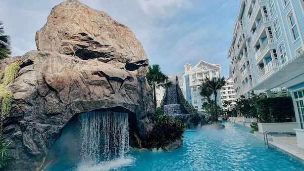 A hotel with a large rock formation, a waterfall, and a pool.