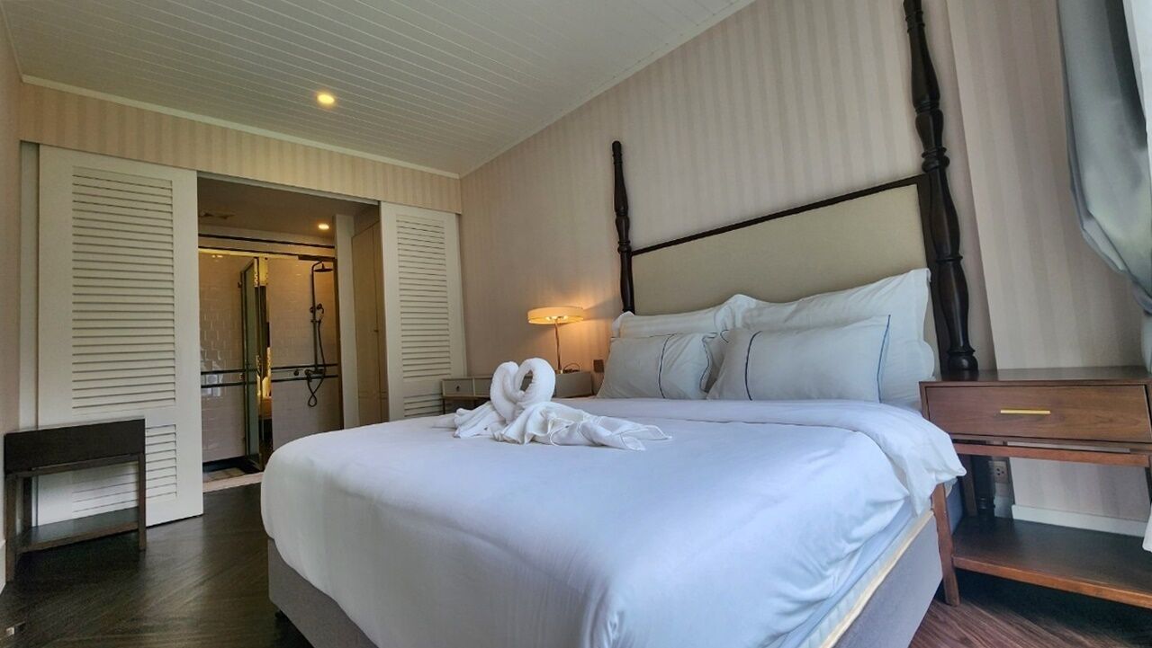 A hotel room with a large bed, a bedside table, a nightstand, a lamp, and a wardrobe with sliding doors.