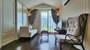 A room with a sofa, a chair, a small table, and a television.