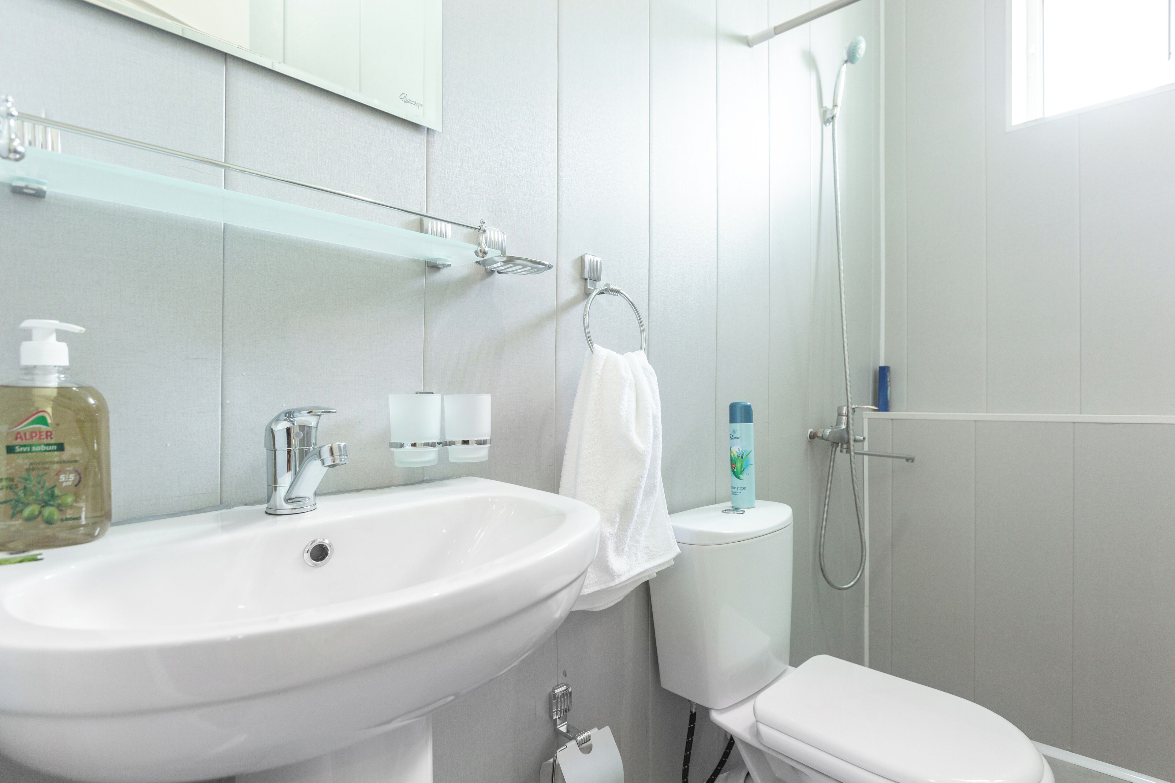 Et badeværelse med en hvid vask, toilet og brusebad.