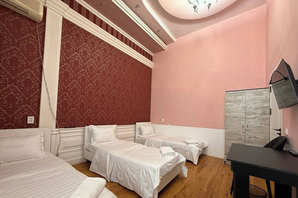 A hotel room with three beds, a desk, and a wardrobe.