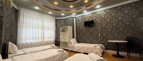 Habitación cuádruple | Espacio para trabajar con laptop y cortinas blackout