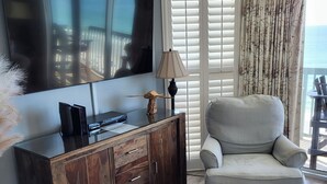 Una sala de estar con televisor de pantalla plana, un mueble de madera y un sillón con cojines.