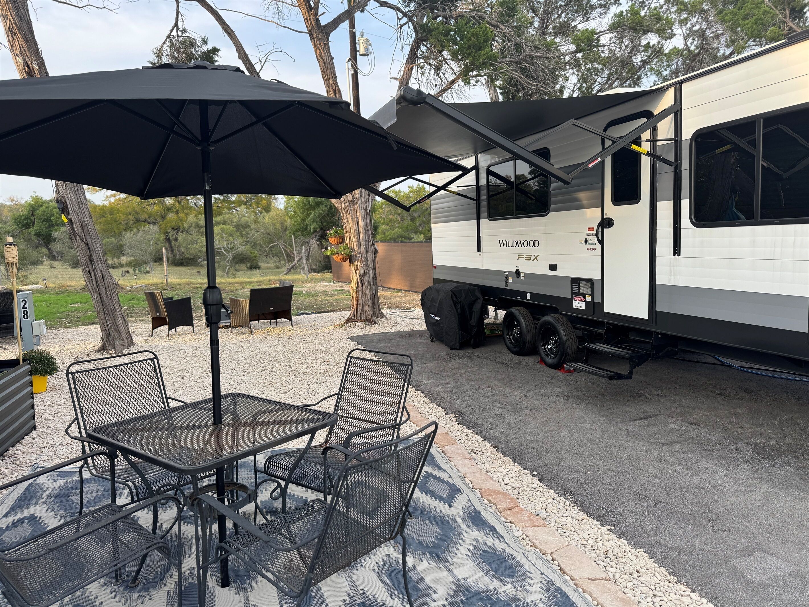 A recreational vehicle with a covered patio area, including a table and chairs.