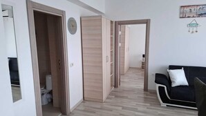 Ein modernes Wohnzimmer mit einer schwarzen Couch, einem Holzschrank und einem Flur, der in einen anderen Raum führt.