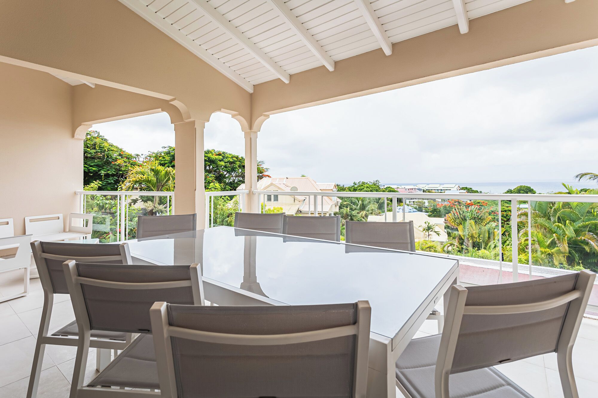 Un espacio de comedor al aire libre con techo, con mesa y sillas, que ofrece vistas panorámicas del océano y vegetación exuberante.