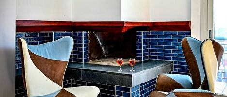 Una cocina moderna con salpicadero de azulejos azules, dos sillas con tapicería de cuero y una chimenea empotrada.