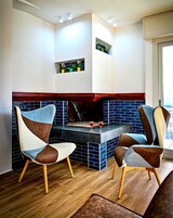 Una cocina moderna con salpicadero de azulejos azules, dos sillas con tapicería de cuero y una chimenea empotrada.