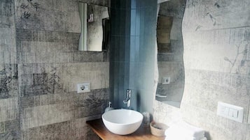 A bathroom with a wooden vanity, a white sink, and a blue shower enclosure.