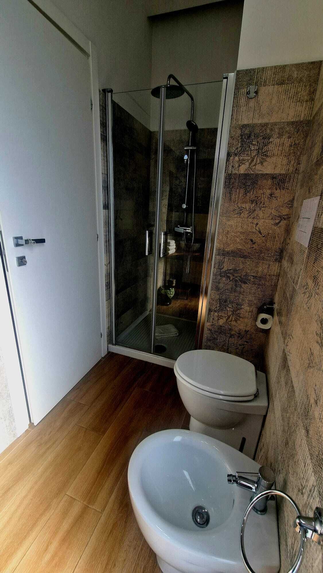 A bathroom with a glass-enclosed shower, a toilet, and a sink.
