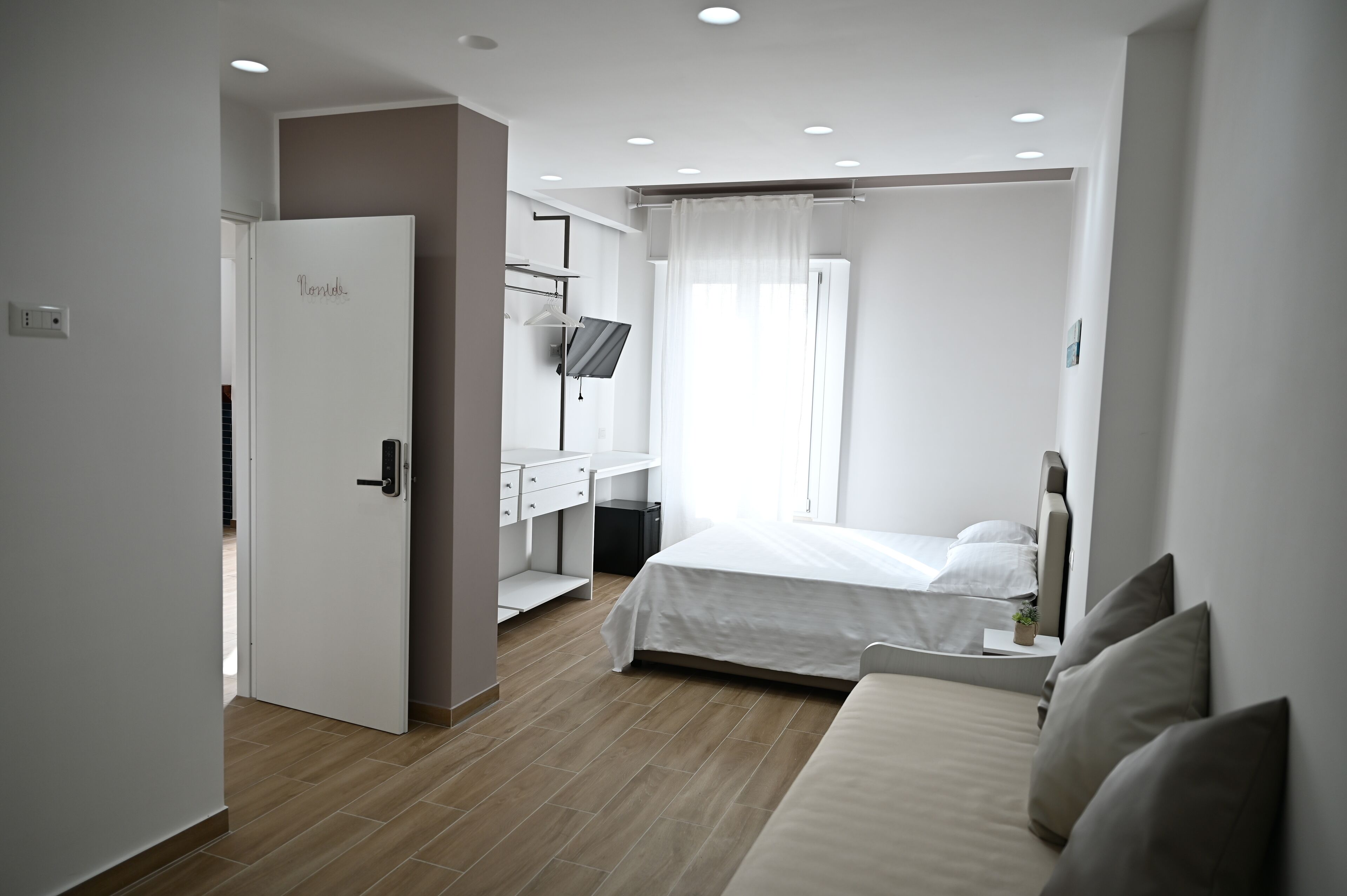 A modern bedroom with a bed, a desk, a TV, and a wardrobe.