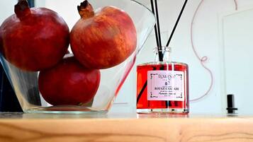A glass bowl containing pomegranates and a bottle of Luxury Italia perfume.