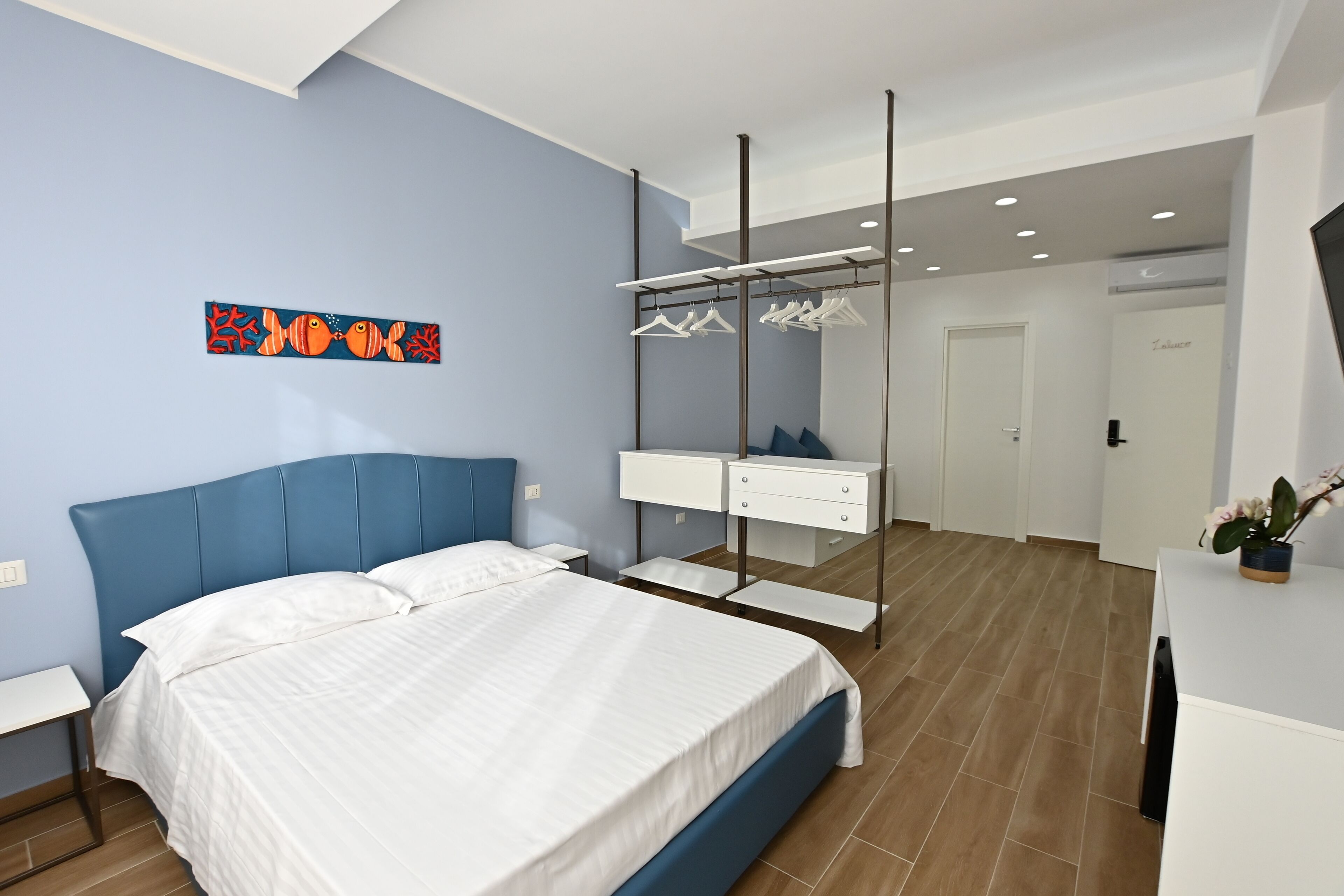 Une chambre à coucher comprenant un lit, une armoire, un miroir et une œuvre d’art murale.