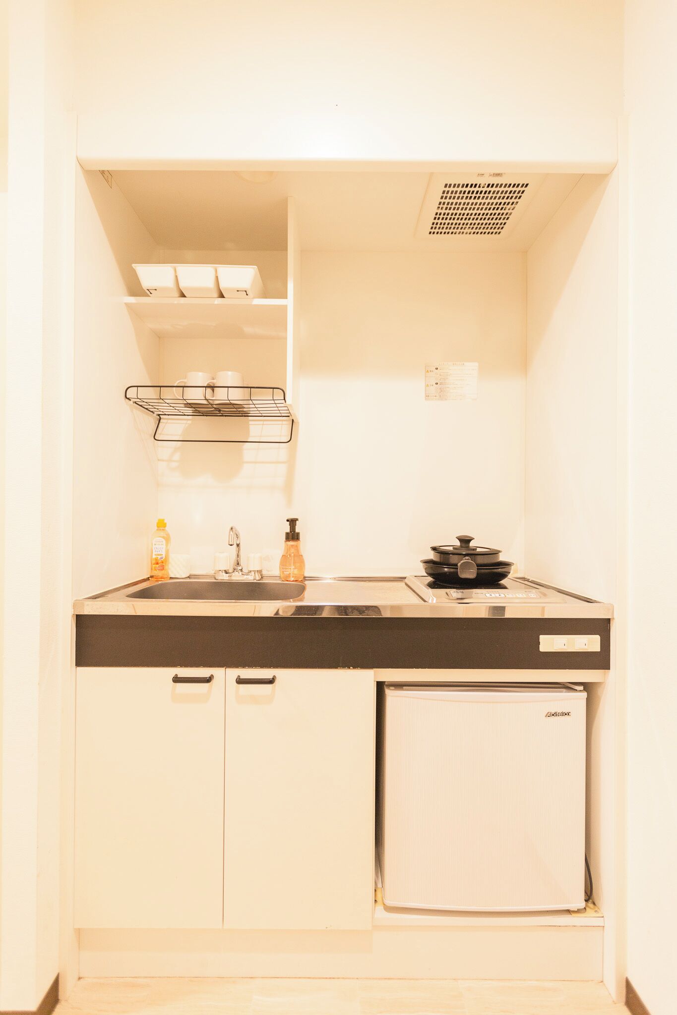 A compact kitchenette with a sink, a small refrigerator, and a stove.