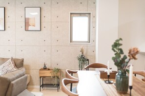 En moderne stue med sofa, spisebord med stole, et lille sofabord og et vindue.