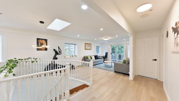A spacious living area with a staircase, a sofa, a dining table, and a view of the outdoors.
