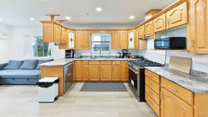 A modern kitchen with wooden cabinets, a built-in microwave, a gas stove, and a grey rug.