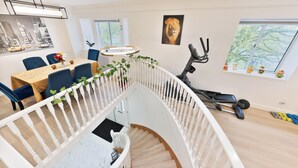 A modern interior with a dining area, staircase, and exercise equipment.