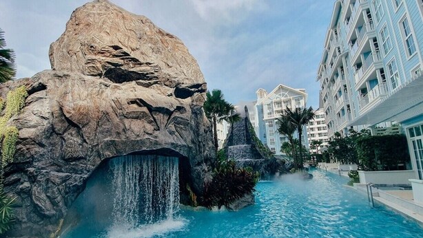 Ein Hotel mit einer großen Felsformation, einem Wasserfall und einem Schwimmbecken.
