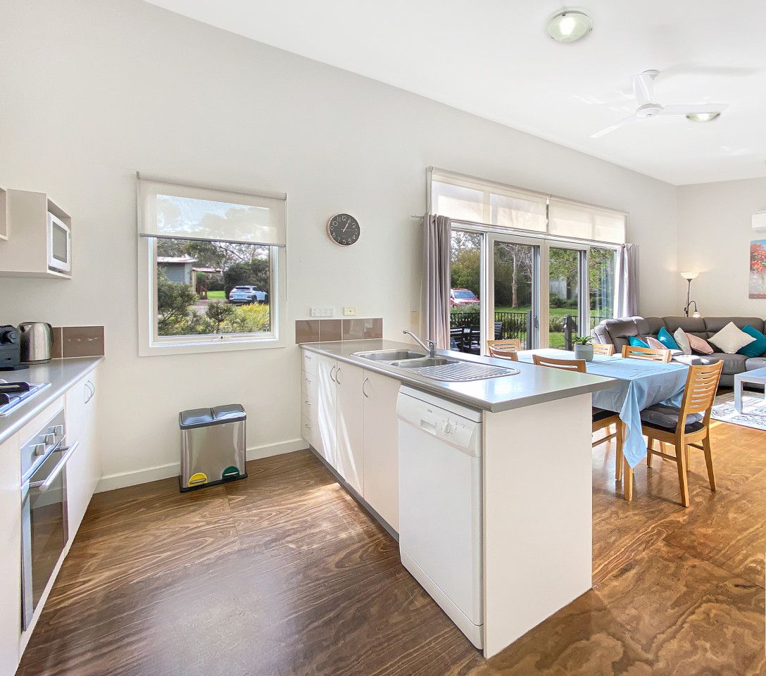 Une cuisine moderne avec un îlot central, un coin repas avec une table et des chaises, un canapé et un tableau au mur.