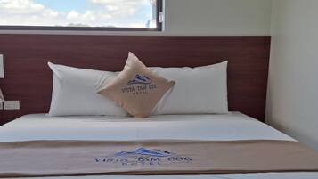 A hotel room with a bed, pillows, and a blanket with the hotel's logo.