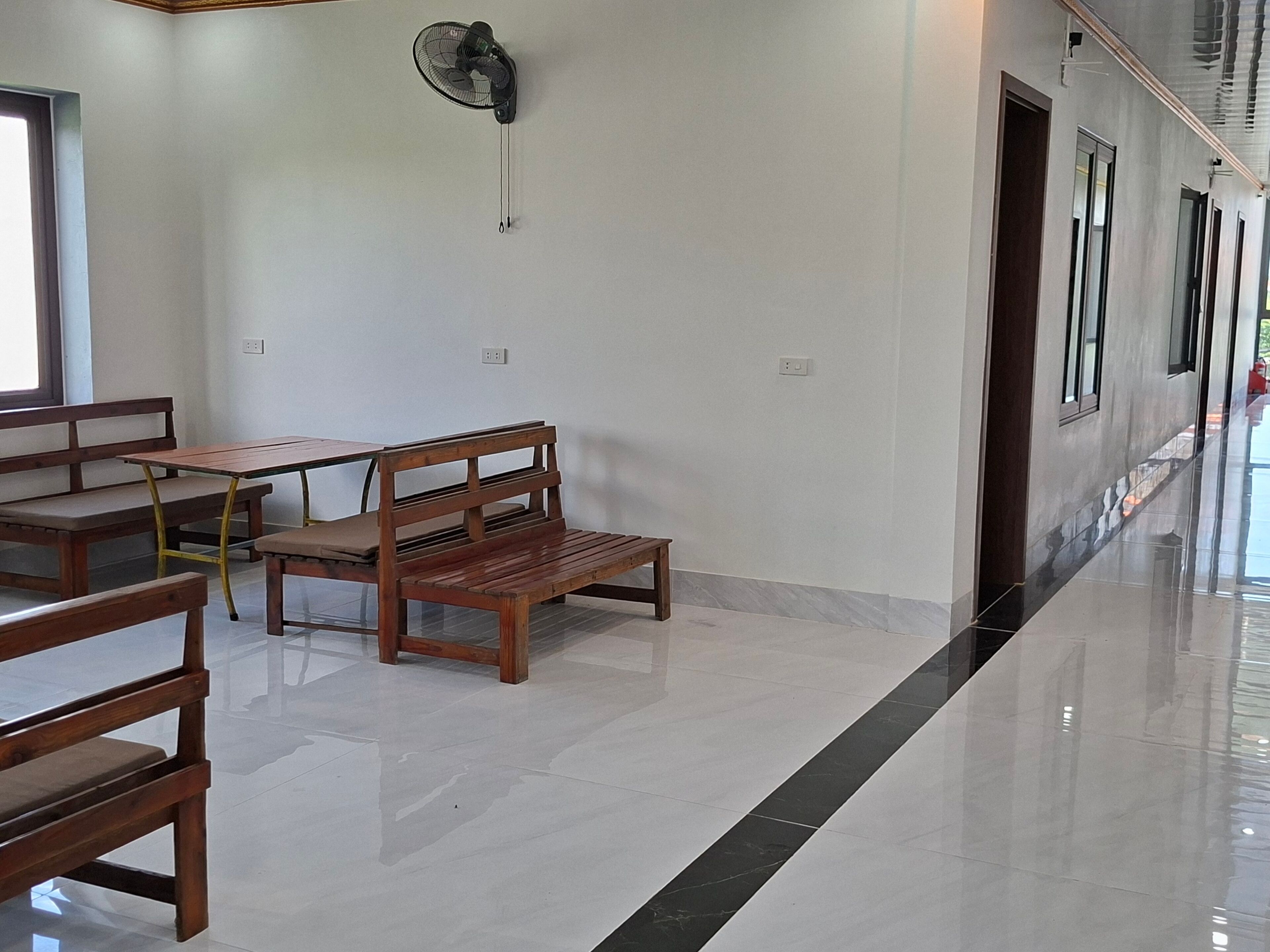 A clean, modern interior with a bench, table, and a wall-mounted fan.