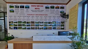 A hotel reception desk with a large informational board displaying tourist information and local attractions. - VISTA TAM COC HOTEL (Nam Hoa Lu)