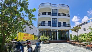 A multi-story building with balconies, a restaurant sign, and parked scooters. - VISTA TAM COC HOTEL (Nam Hoa Lu)