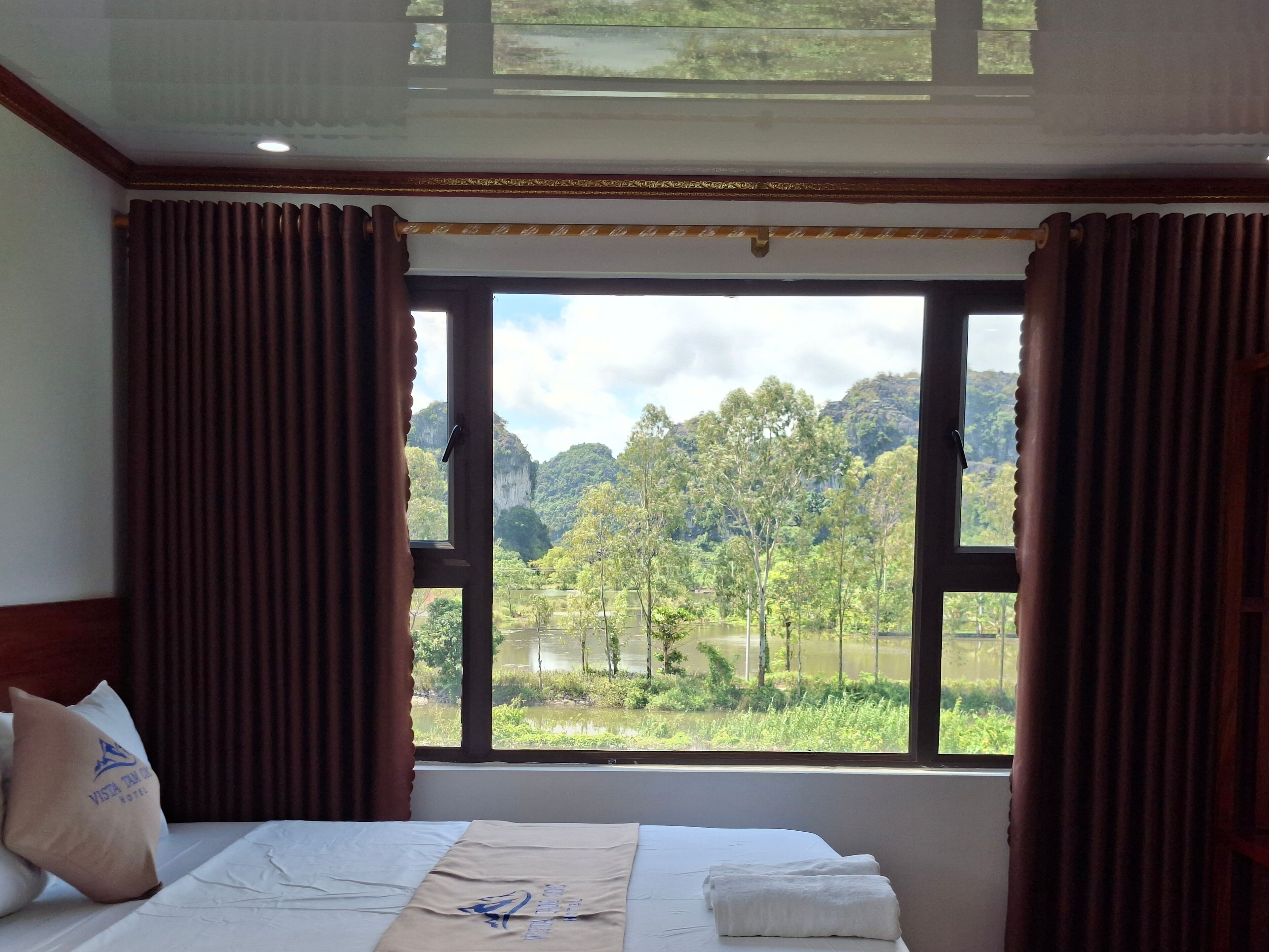 Een hotelkamer met een groot raam, met uitzicht op een bebost gebied en een meer.