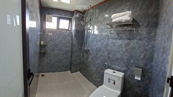 Ein modernes Badezimmer mit Toilette, Dusche mit Duschbrause, Handtuchhalter und einem Fenster für natürliches Licht.