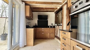 A modern kitchen with wooden cabinets, a built-in oven, and a large window.