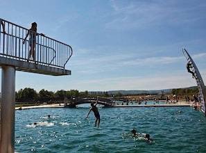 A swimming pool with a bridge, people swimming, and a person diving.