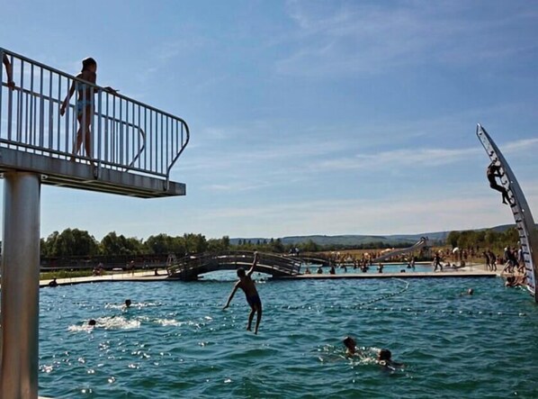 A swimming pool with a bridge, people swimming, and a person diving.