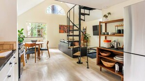 Una cocina moderna con una escalera de caracol, suelo de madera y un comedor con mesa y sillas.
