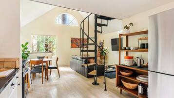A modern kitchen with a spiral staircase, wooden flooring, and a dining area with a table and chairs.