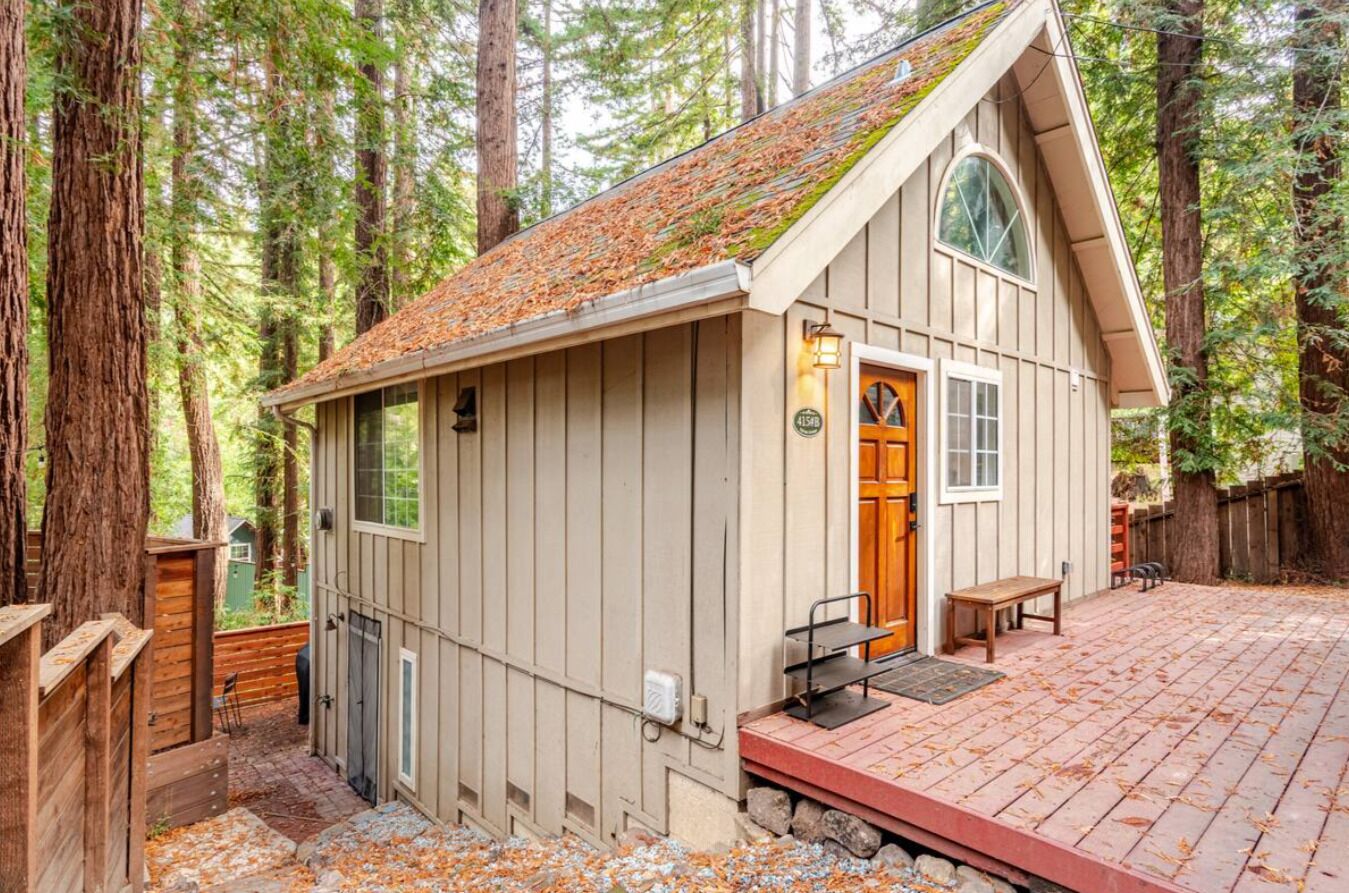 A cabin with a wooden deck, a front door, and a small porch.